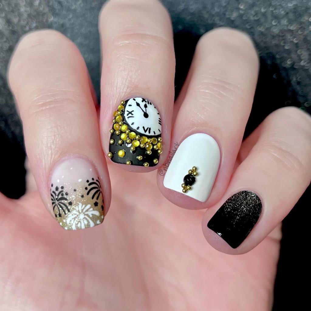 New Year's Eve nail art featuring fireworks, a clock, gold accents, and a classic black and white color scheme.