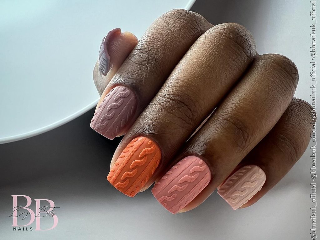 Stylish multicolor nail art featuring textured wave patterns in peach, orange, and pink shades.