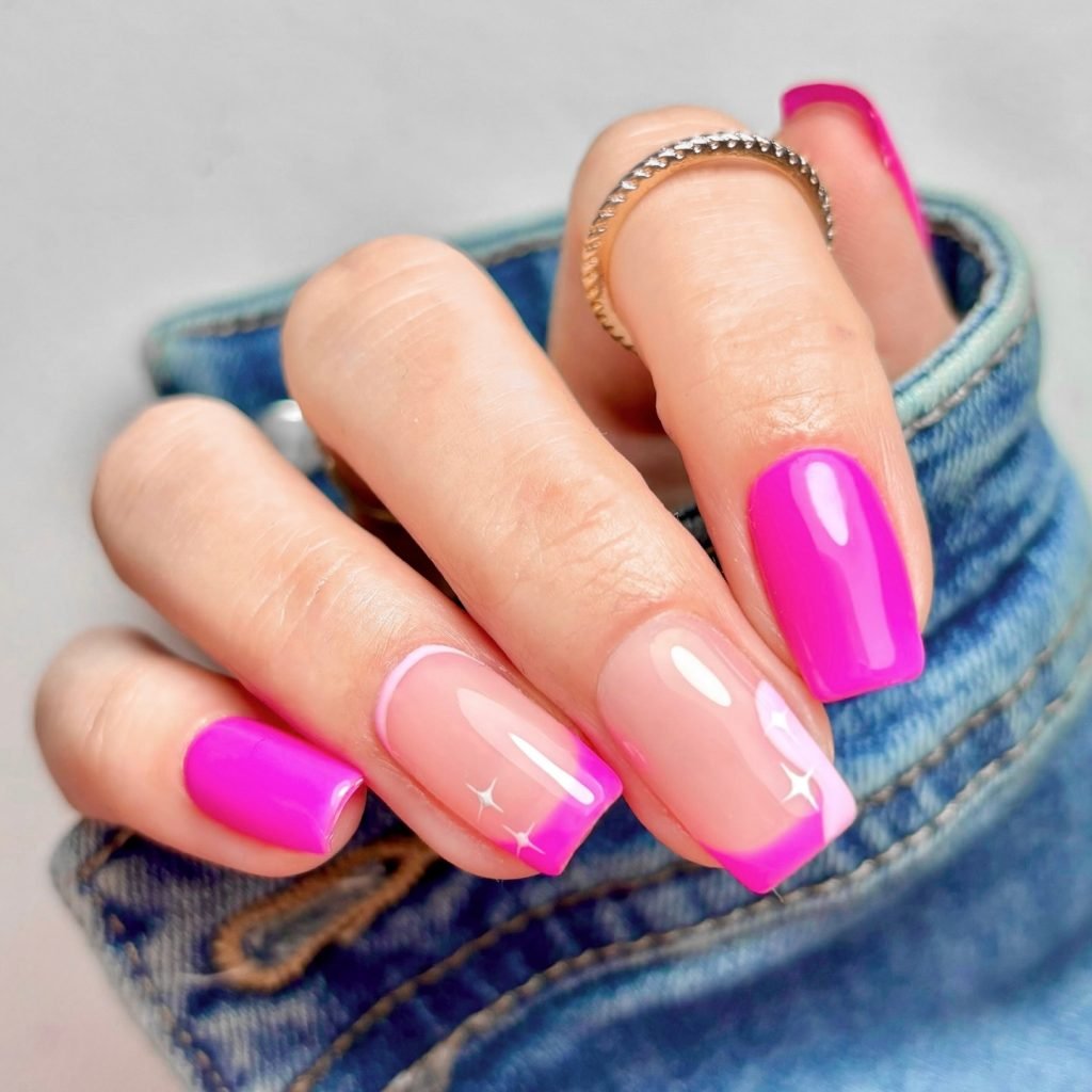 Vibrant pink and nude manicure with a glossy finish and sparkling accents, paired with a denim jacket.