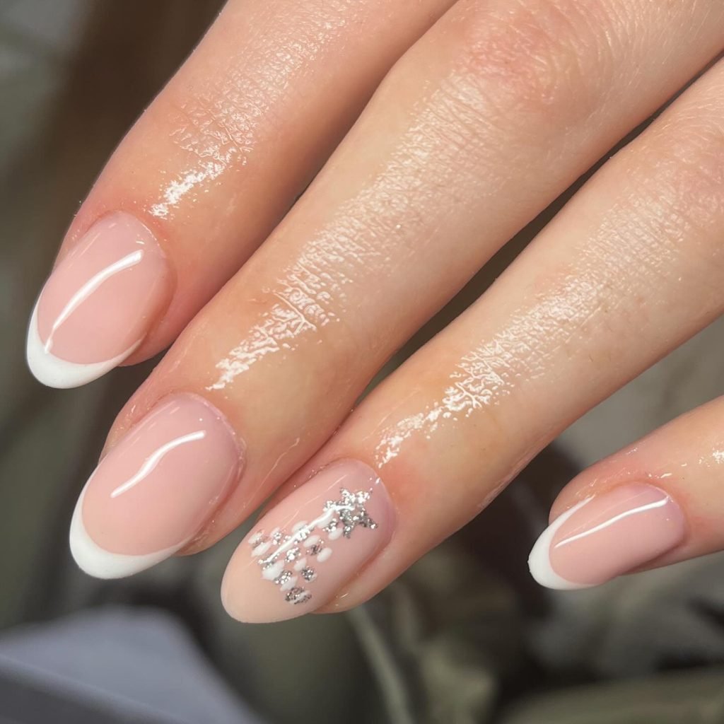 Elegant French manicure with silver star accents on ring finger against a soft pink base. Perfect for a classy look.