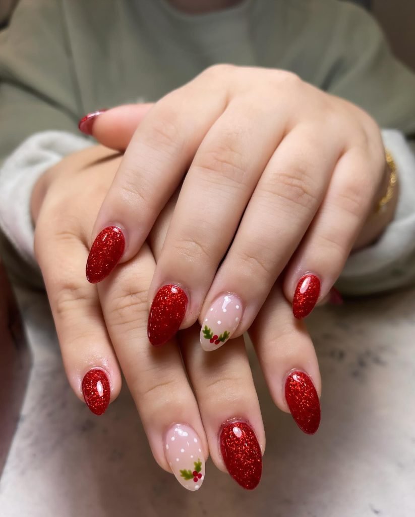 Red glitter holiday nails with festive holly design on nude accent nails. Close-up of stylish manicure.