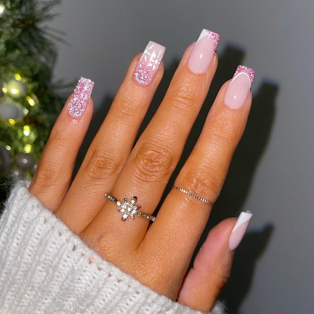 Festive pink glitter nail art with snowflake design and rings, perfect for winter style.