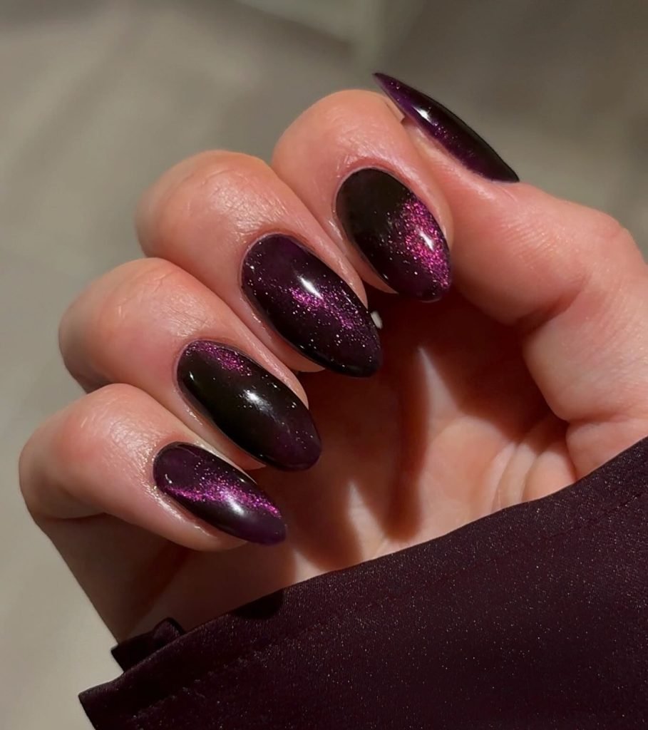 Dark purple gradient nails with pink glitter accents on a hand, close-up view.