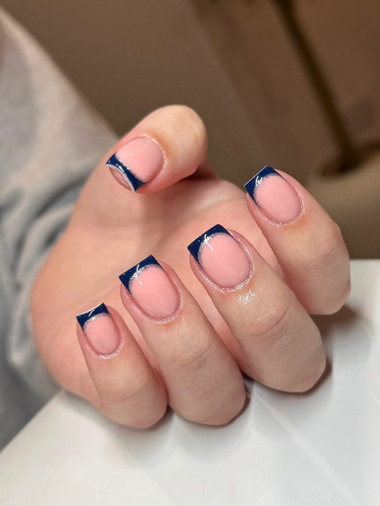 Stylish nails with pink polish and navy blue French tips, showcasing elegant nail art design.