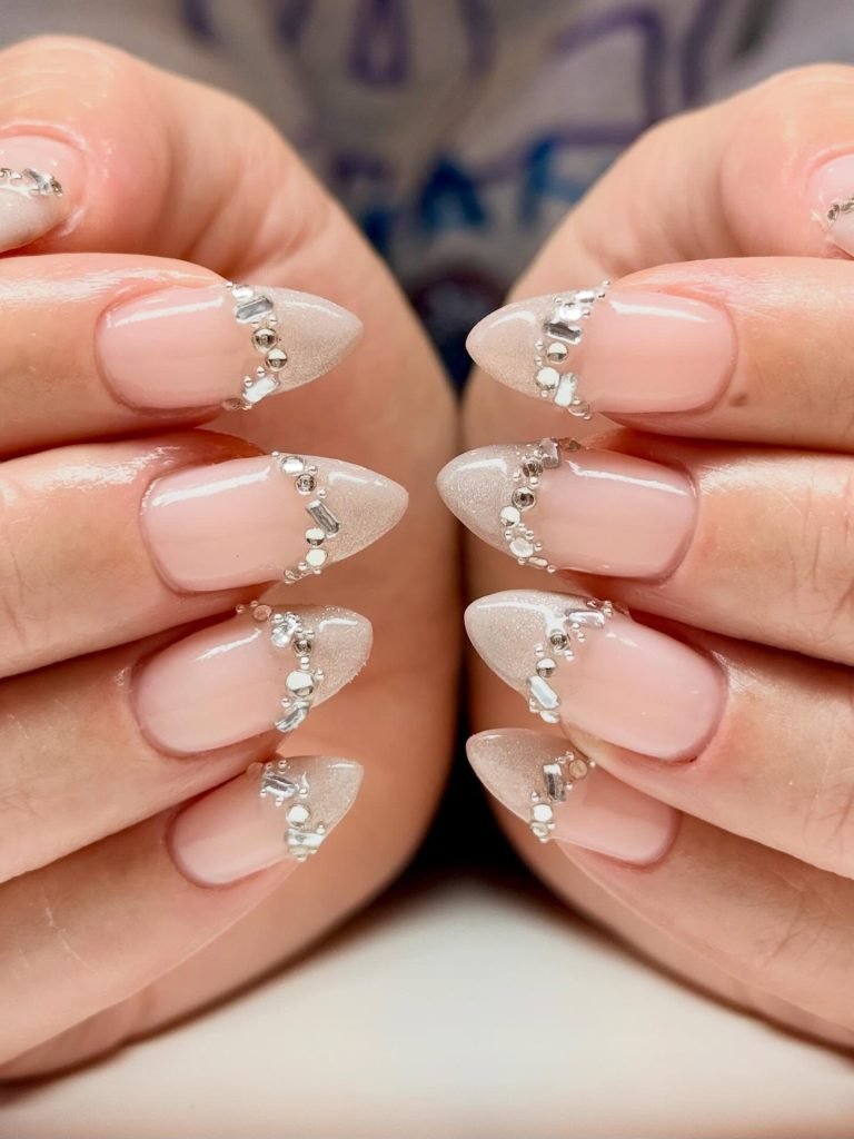 Sparkling stiletto nails with rhinestone accents and nude polish, perfect for elegant nail art inspiration.