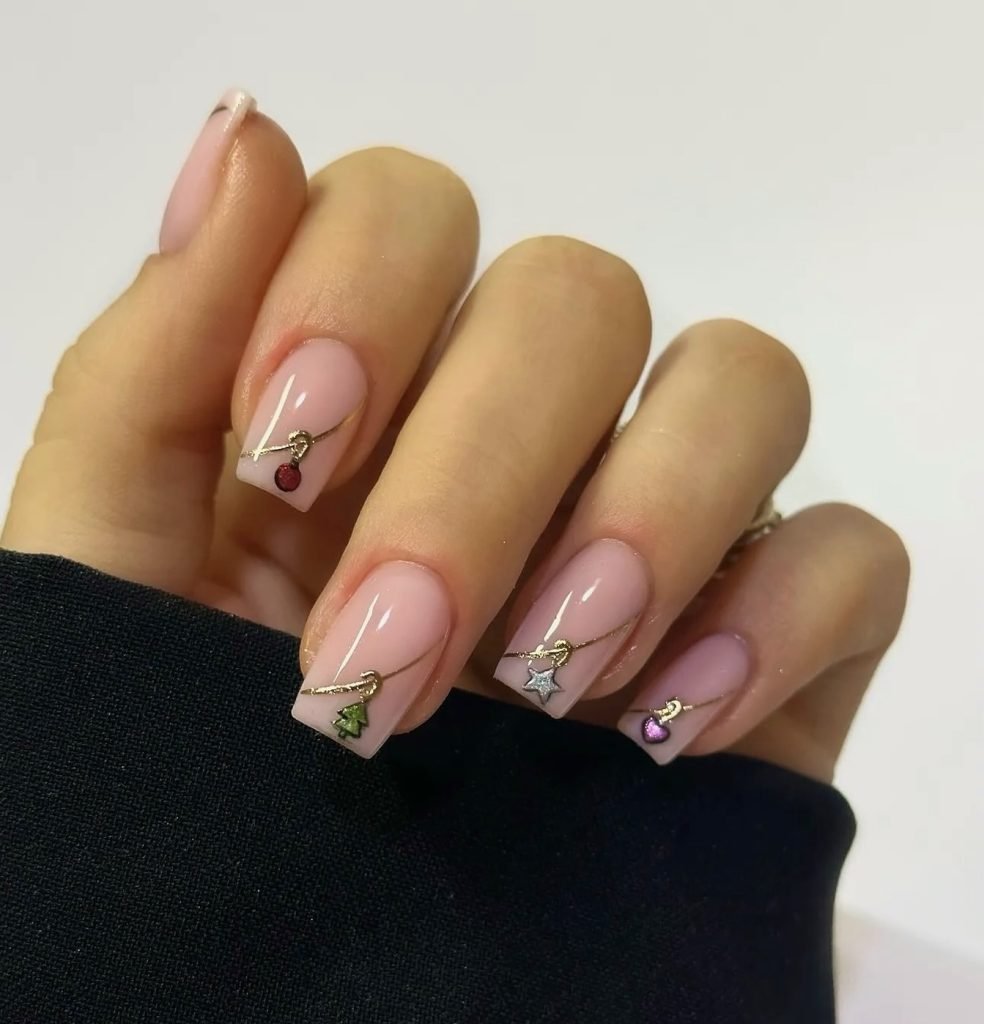 Close-up of elegant pink manicure with festive charms on acrylic nails.