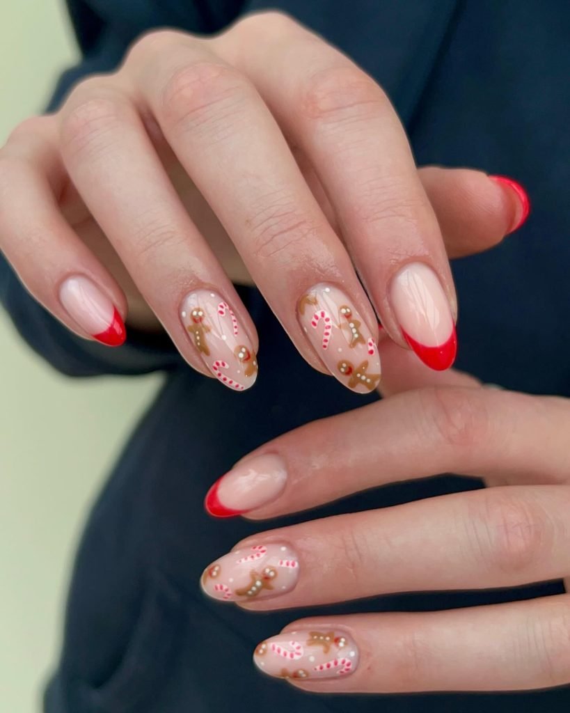 Holiday-inspired nail art with gingerbread men and candy canes on red-tipped nails.