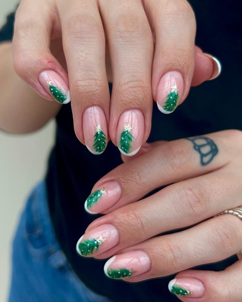 Festive nail art with green Christmas tree designs and glitter accents on a shiny pink base. Perfect for holiday season.