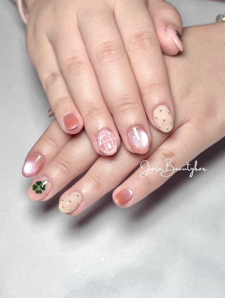 Stylish nail art with peach and beige design, featuring a shamrock and grid pattern accents. Perfect manicure inspiration.