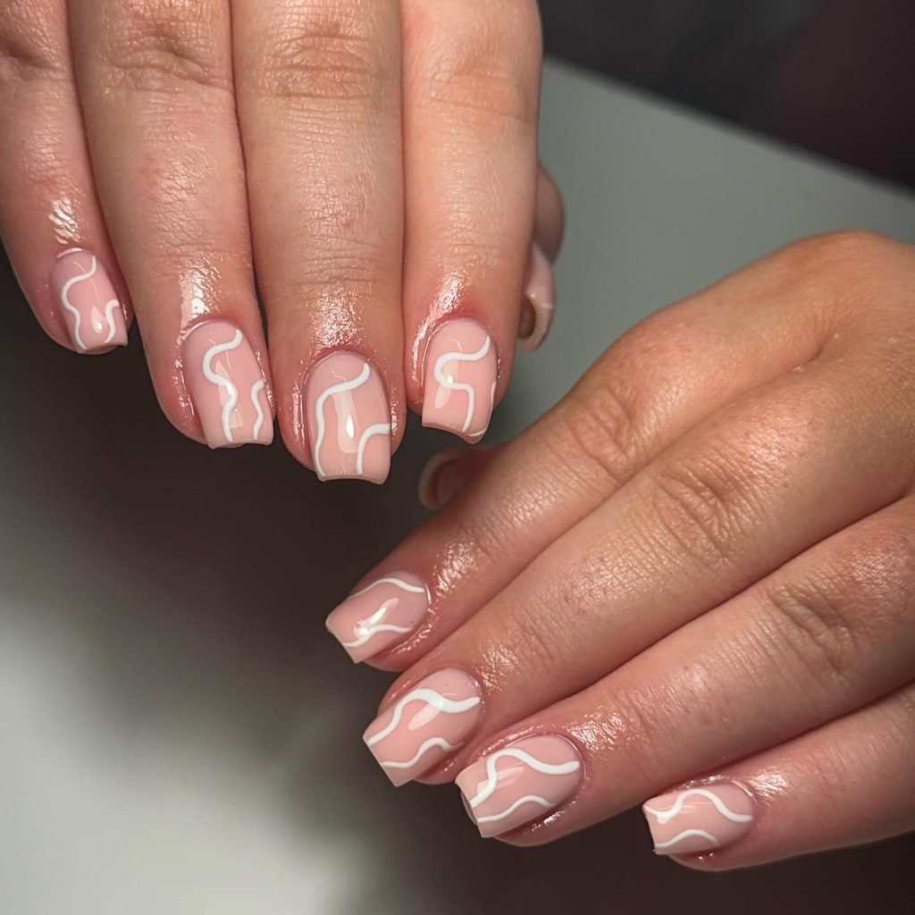 Stylish pink nails with white abstract wave design, perfect for chic, modern nail art inspiration.