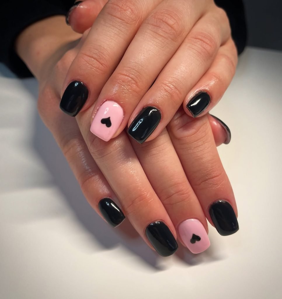 Black and pink manicure with heart nail art, showcasing trendy nail design on short nails.