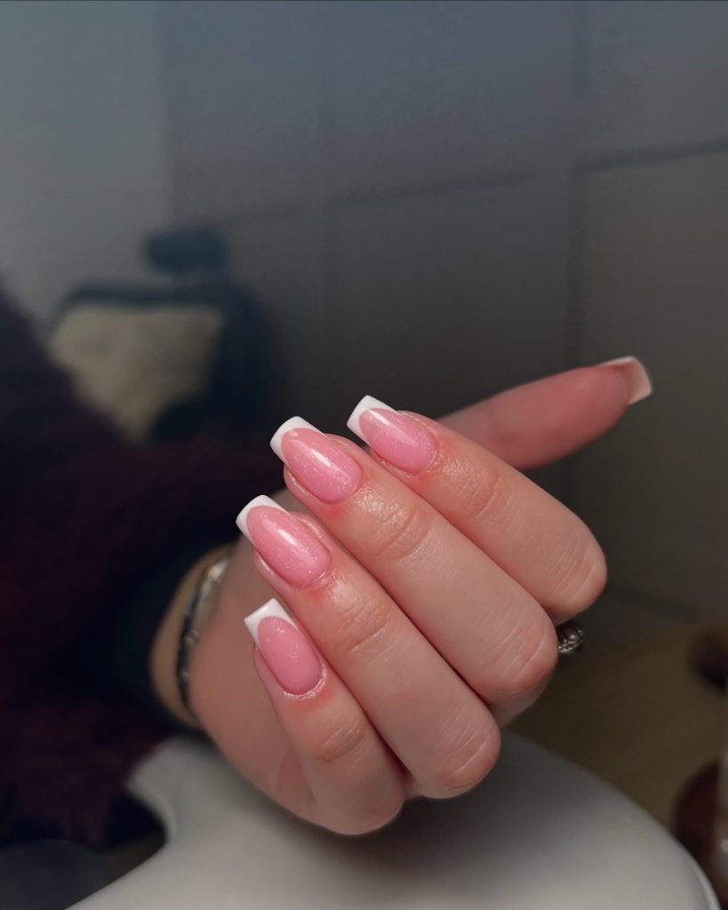 Pink and white French manicure nails, elegantly styled and polished, hand close-up.