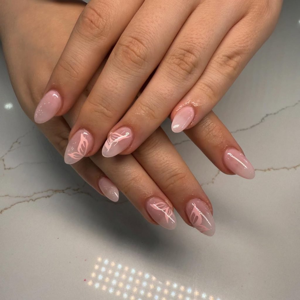 Elegant pink ombre nails with white floral designs on a marble background, showcasing chic and stylish manicure trends.