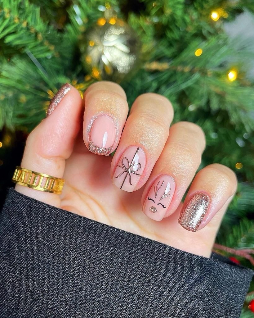 Festive nails with glittery tips and Christmas-themed artwork, perfect for holiday celebrations.