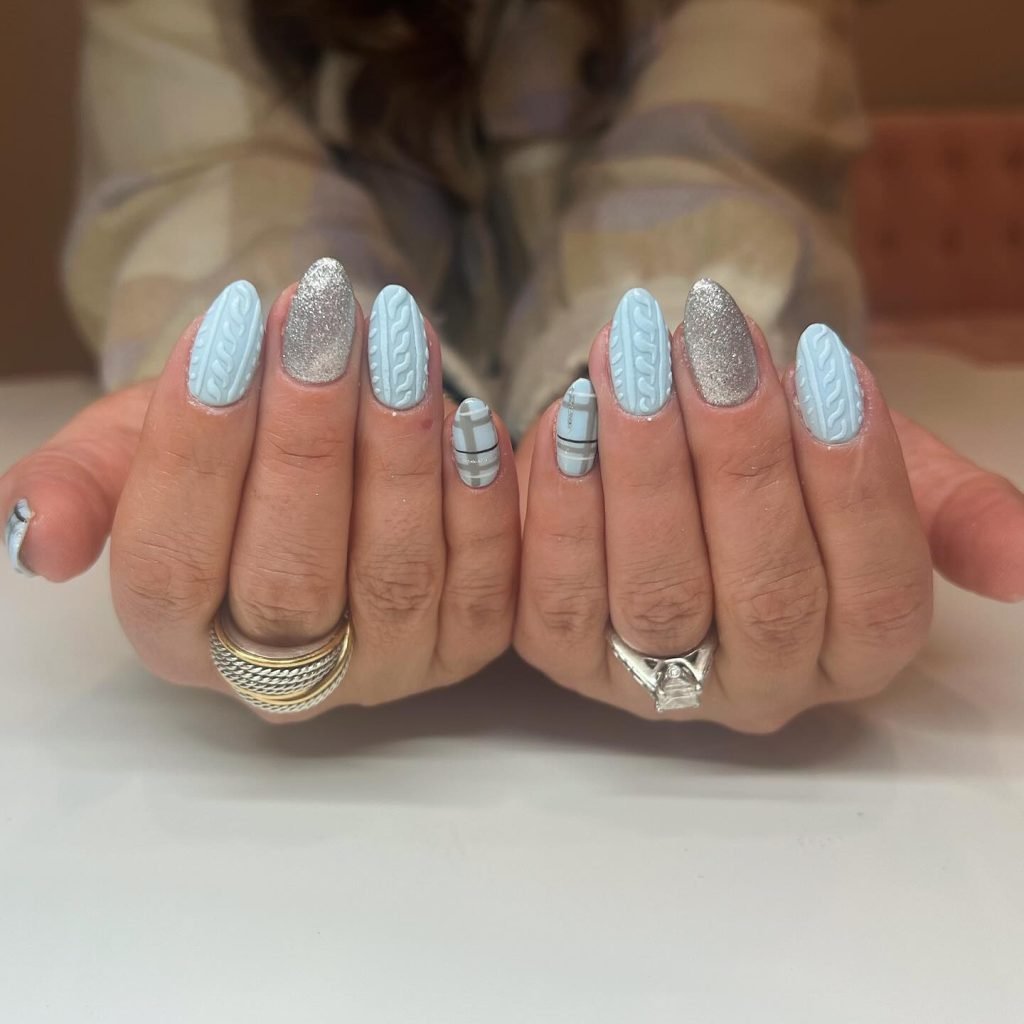 Blue and silver nail art with knit patterns and plaid design on almond-shaped nails.