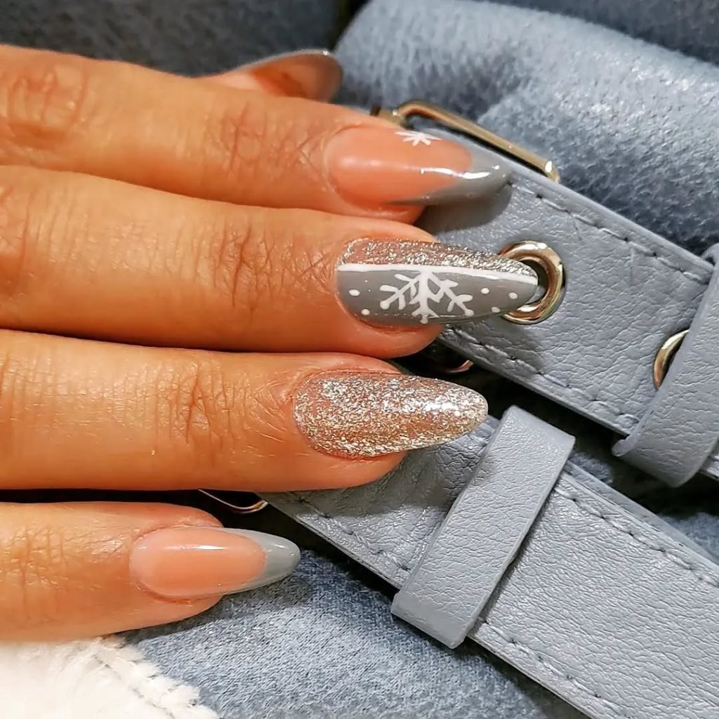 Stylish nails with snowflake, sparkles on a blue leather purse, winter-themed manicure design.