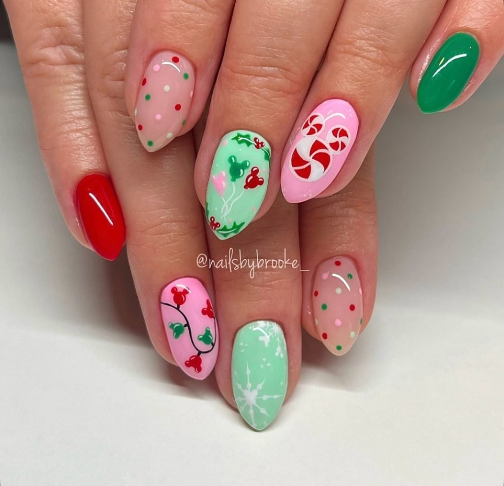 Festive Christmas nail art with candies, holly, and polka dots in red, green, and white on manicured hands.