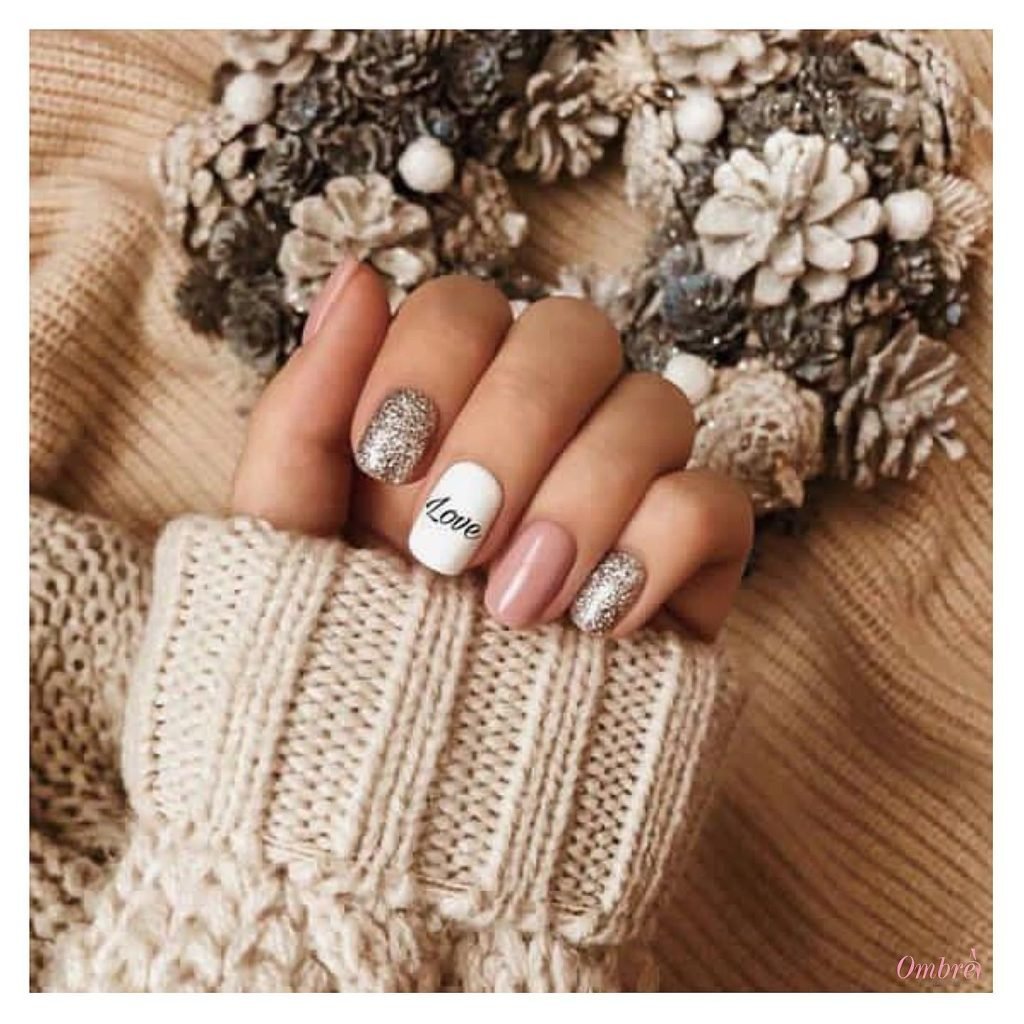 Cozy winter nails with glitter and Love accent, paired with a knit sweater and festive wreath in the background.