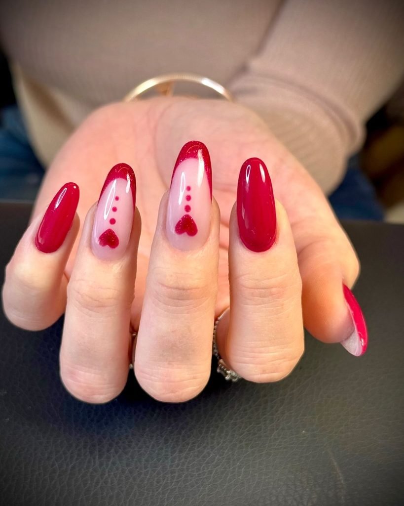 Red nail art with heart designs on long nails, perfect for Valentine's Day or a stylish, romantic look.