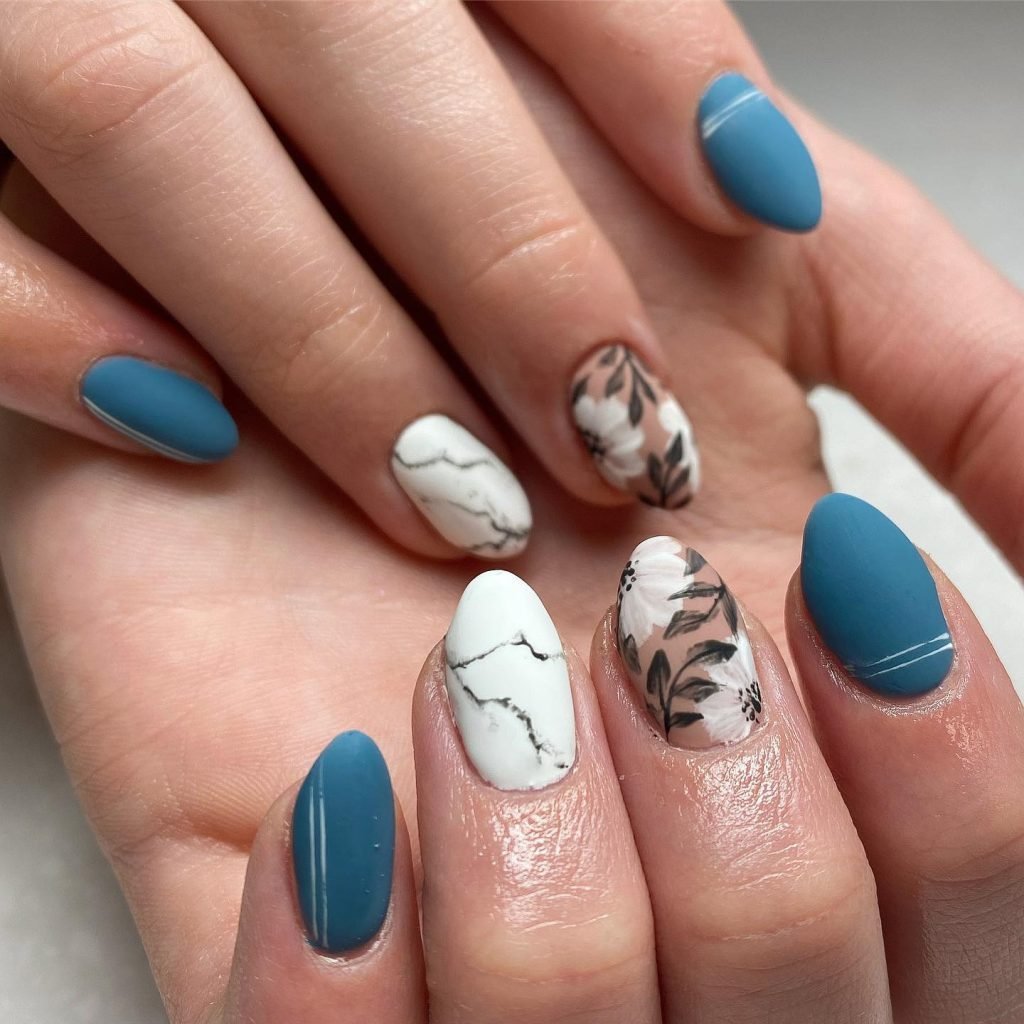 Blue and white floral nail art design with marbled accents on manicured nails.