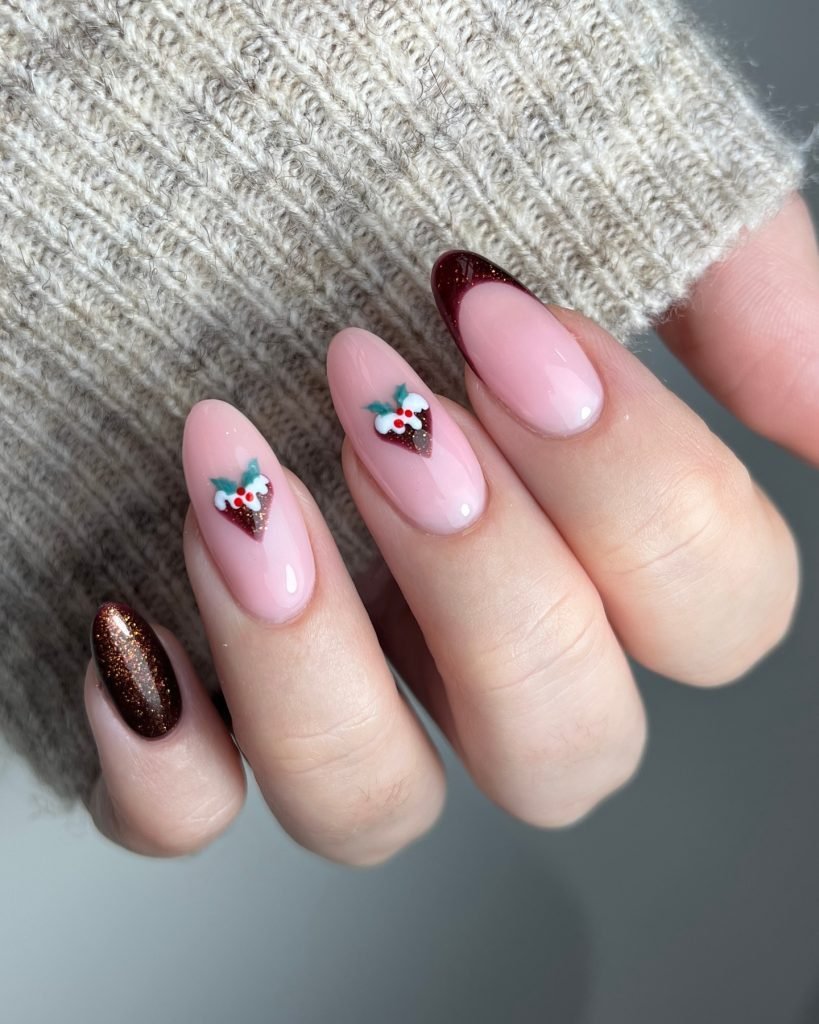 Festive nail art featuring chocolate and pink designs with holiday-themed embellishments on a cozy sweater background.