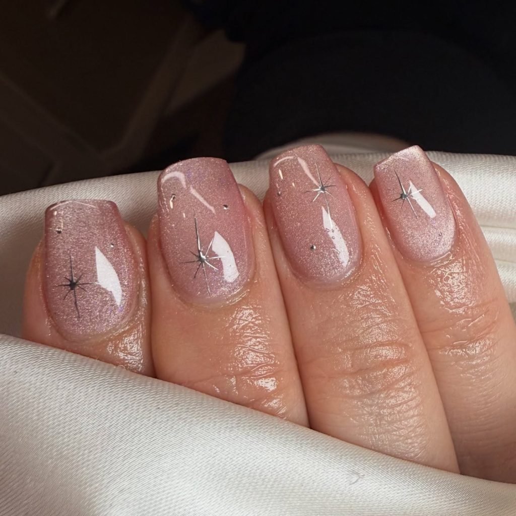 Sparkly pink manicure with silver star accents, perfect for a chic and glamorous nail look.