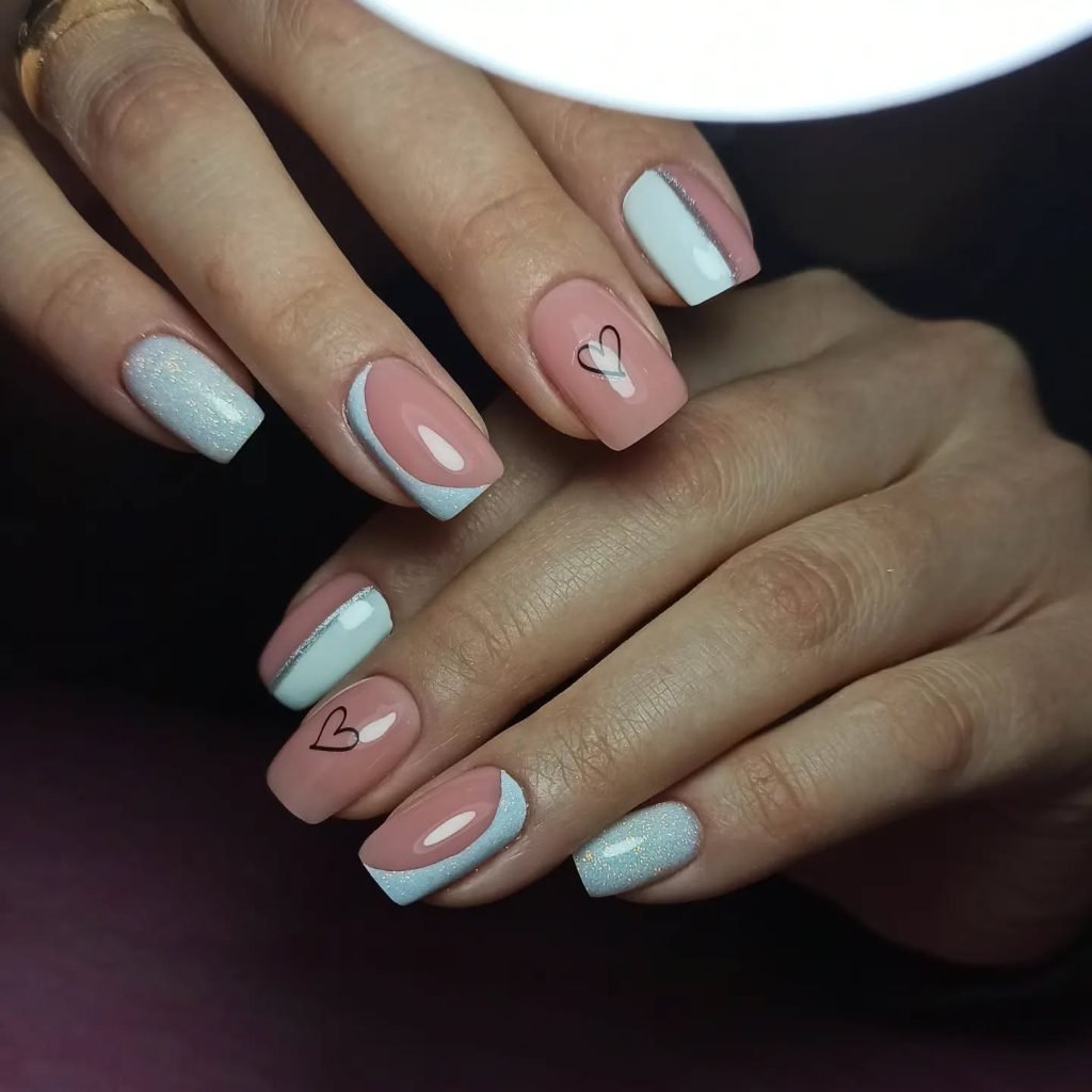 Elegant pink and white nails with heart designs on a woman's hands, perfect for a chic and stylish manicure look.