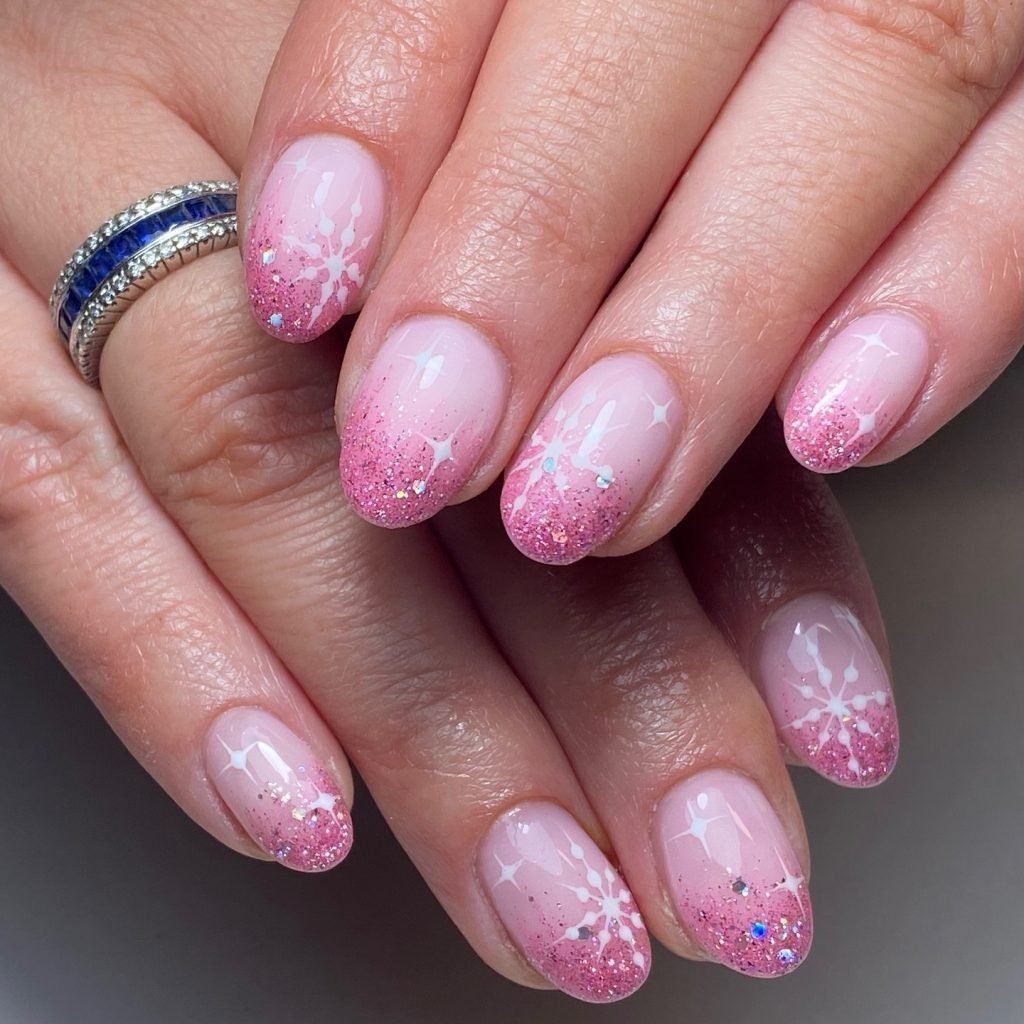 Close-up of hands with pink glitter and snowflake nail art, wearing a sapphire ring.