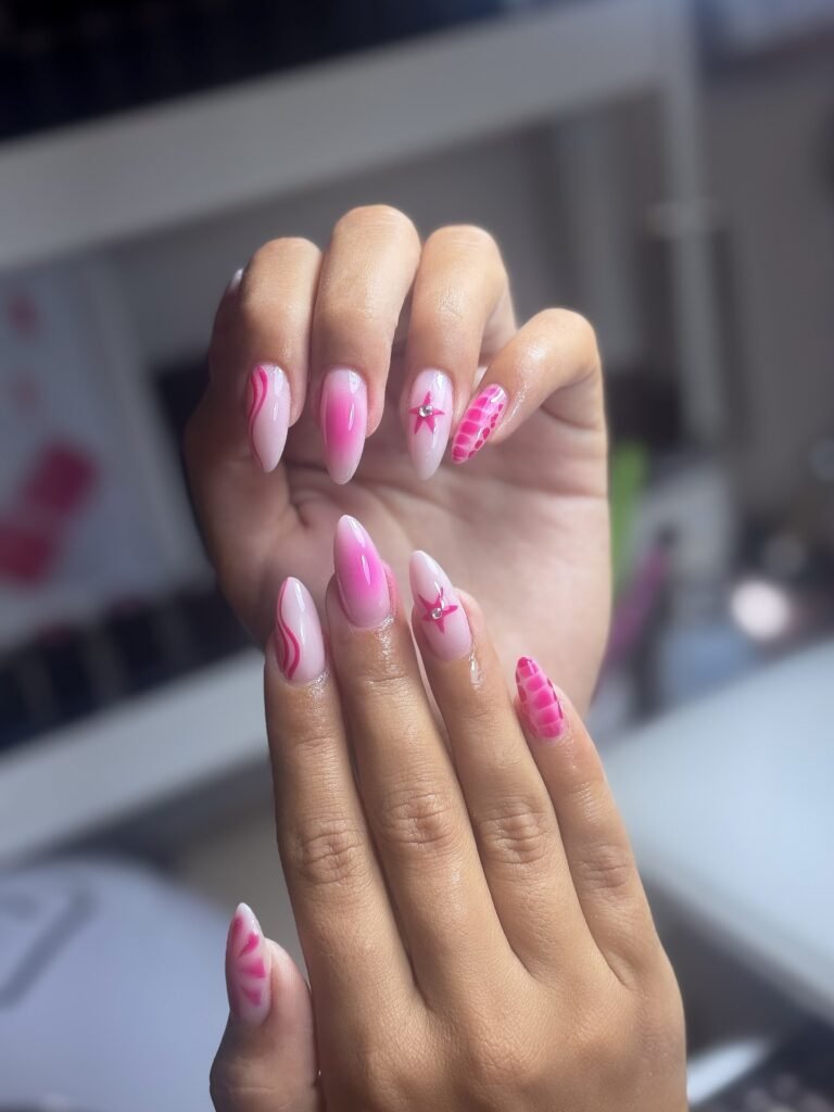 Pink nail art with star and swirl designs on long almond-shaped nails. Elegant manicure for style inspiration.