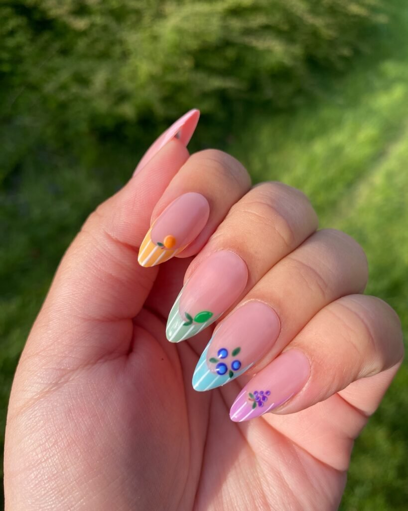 Hand with colorful floral nail art, featuring pastel shades and small flower designs, outdoor setting in sunlight.