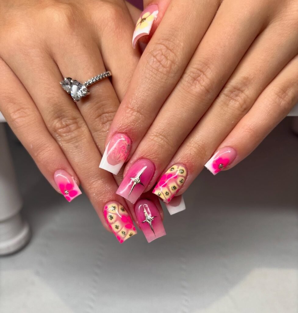 Colorful floral and rhinestone nail art on manicured hands with a stylish ring.