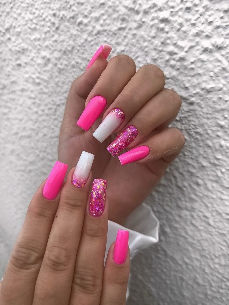Bright pink and white ombre nails with glitter accents, showcasing trendy square-shaped manicure design.