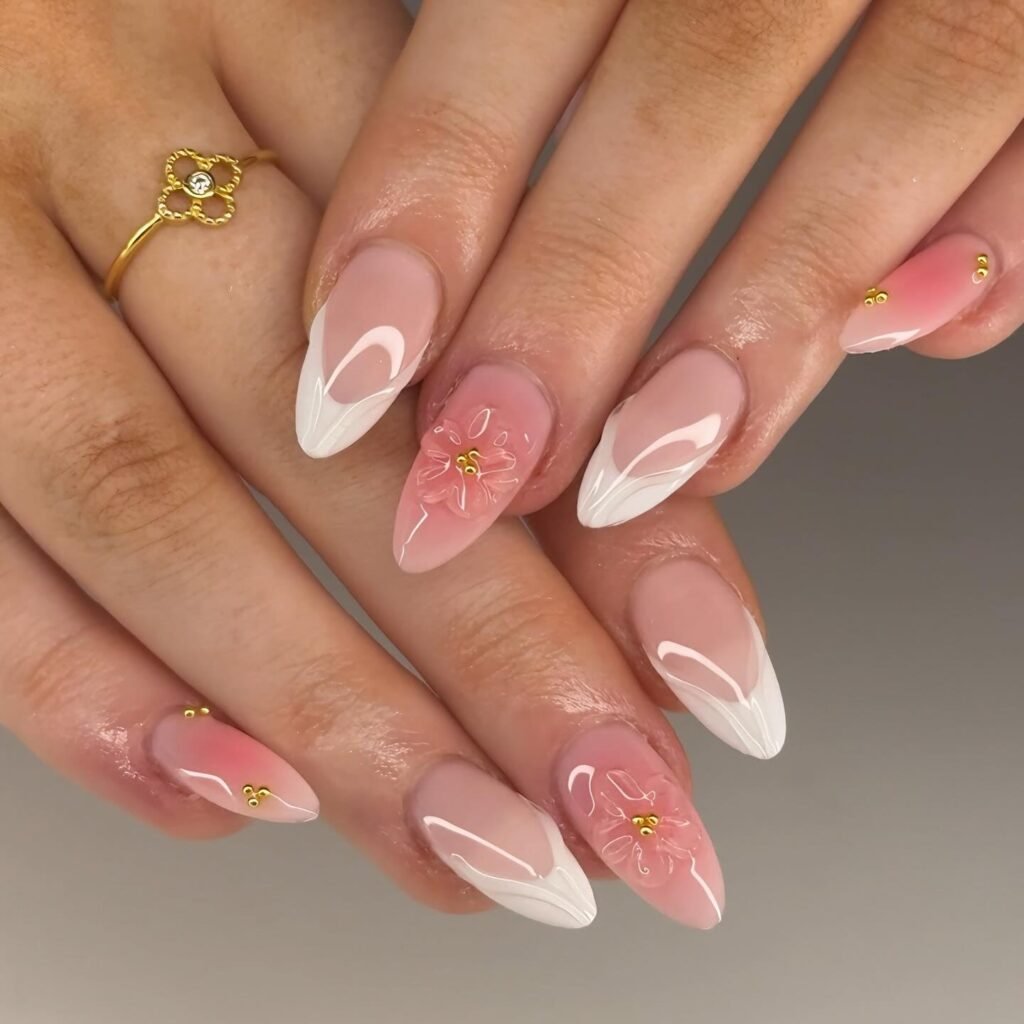 Elegant nail art with pink and white floral design, featuring gold accents on almond-shaped nails.