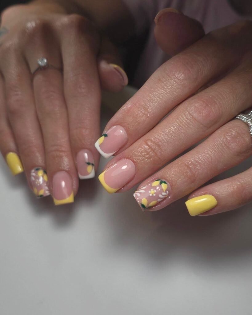 Yellow and floral nail art with French tips, displayed on manicured hands.