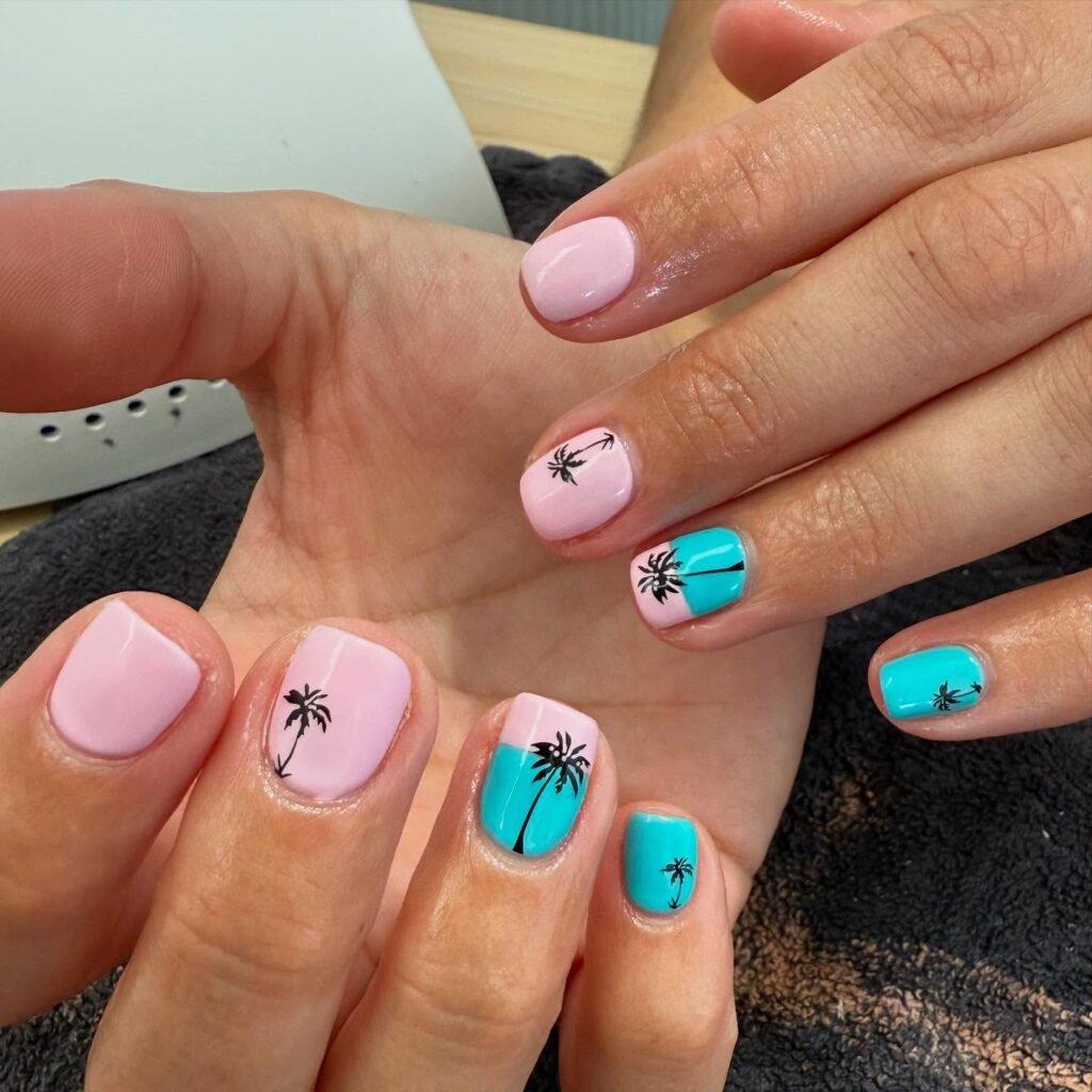 Pastel pink and blue nails with palm tree designs, perfect for a tropical summer look.