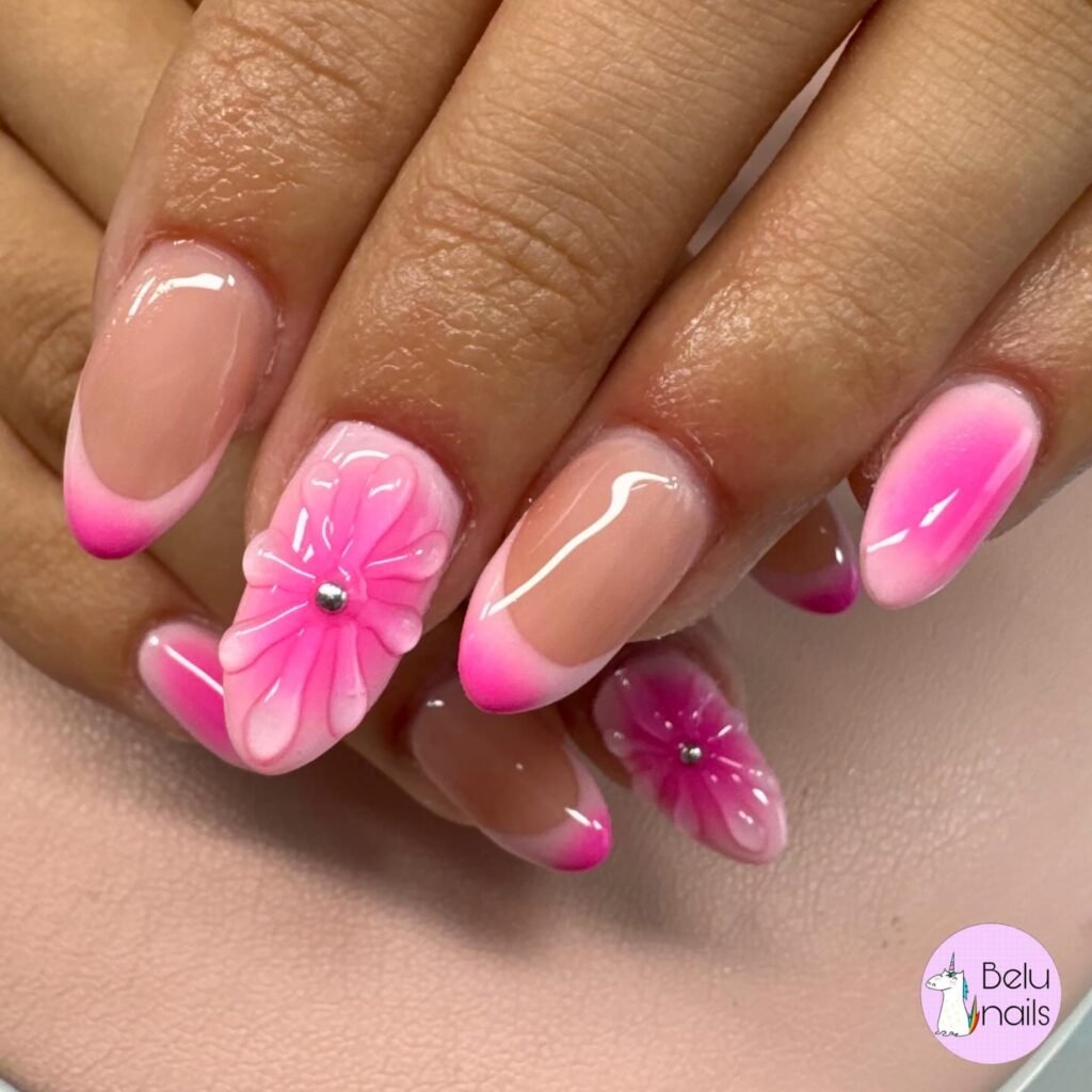 Pink floral nail art with elegant French tips featuring glossy finish and rhinestone accents on manicured nails.