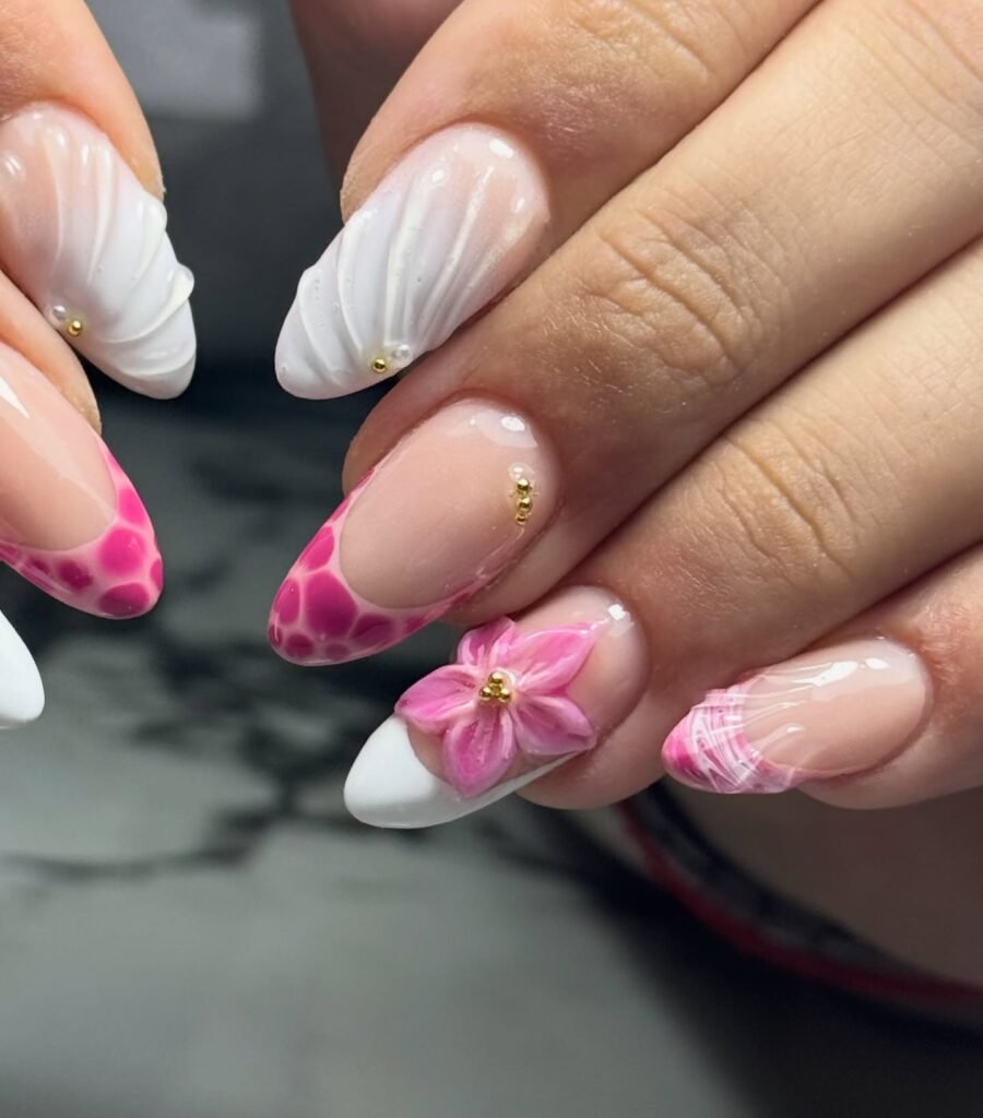 Elegant pink and white 3D floral acrylic nail art with gold accents on manicured hands.