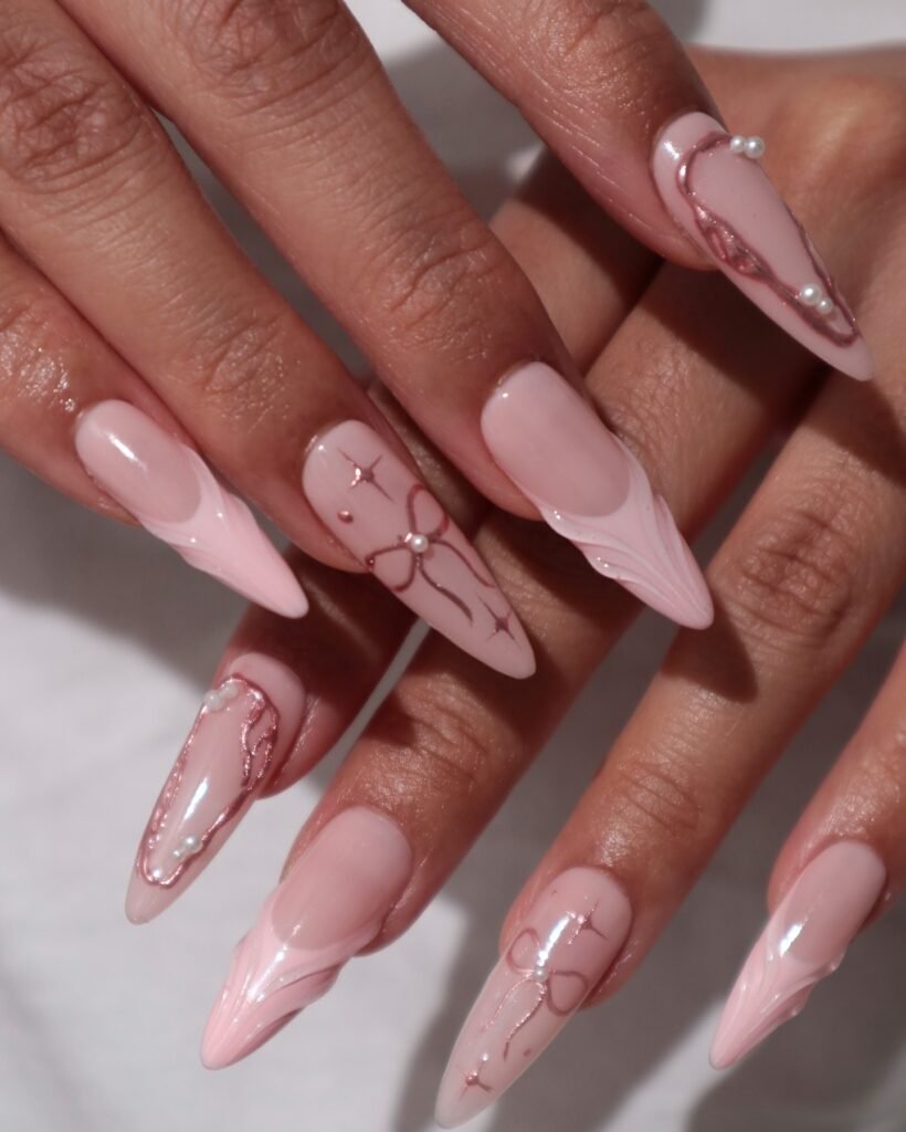 Elegant pink nail art with pearl accents and delicate line designs on long, almond-shaped nails.