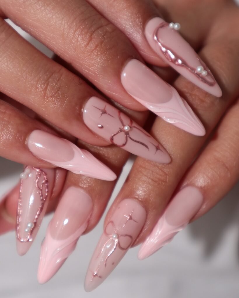 Elegant pink stiletto nails with pearl accents and intricate designs, showcasing a chic and stylish manicure.