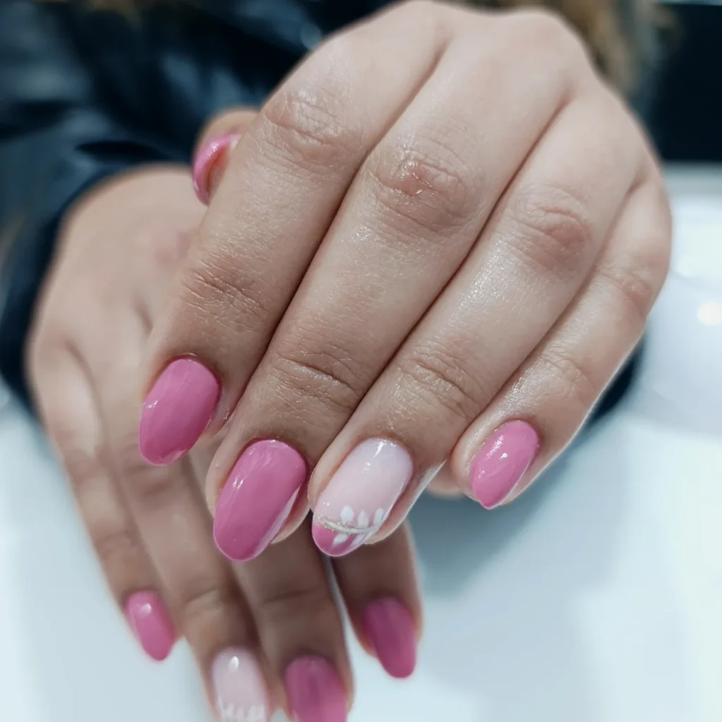 Pink nail art with elegant white designs, showcasing a stylish manicure on neatly manicured hands.