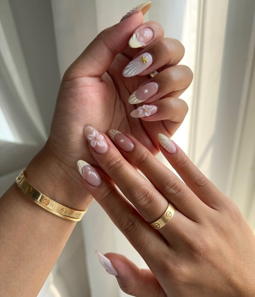 Close-up of hands with elegant floral and textured nail art, wearing a gold bracelet and ring, soft lighting.