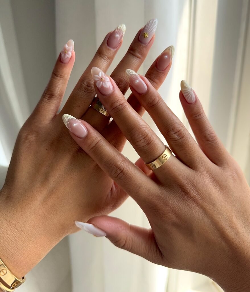Elegant almond-shaped nails with floral designs and gold rings.