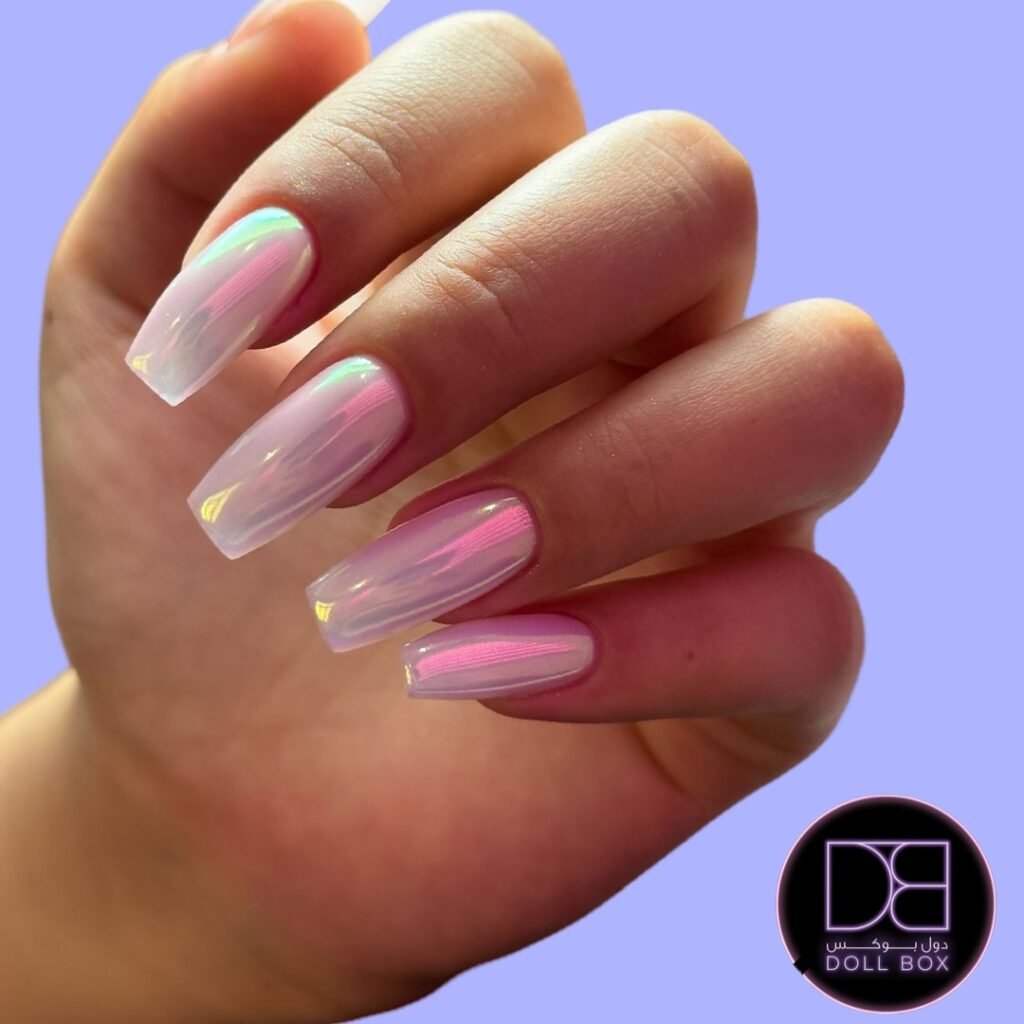 Close-up of a hand with shiny holographic pastel pink nails, set against a light purple background.