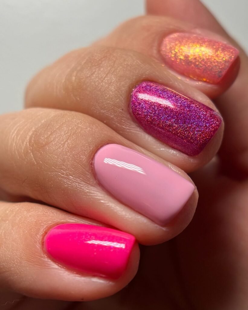 Colorful manicured nails with pink, glittery, and gradient designs. Perfect for a vibrant, stylish nail art look.