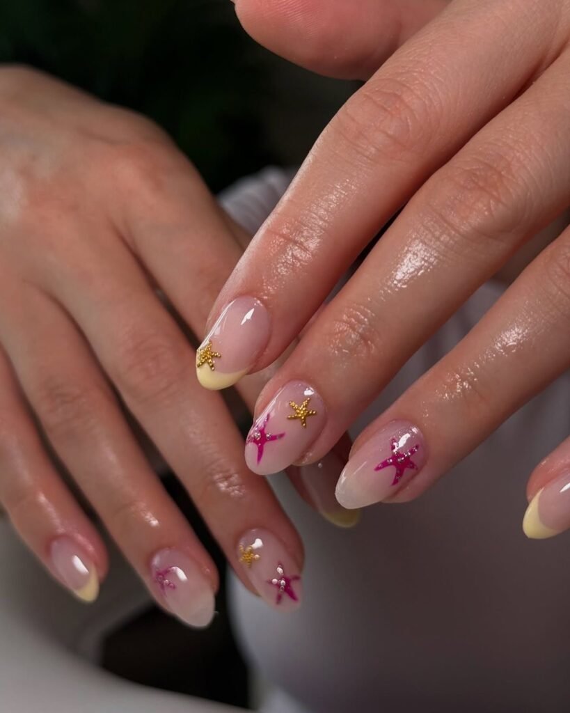 Close-up of hands with starfish-themed nail art in pink and gold on neatly manicured nails.