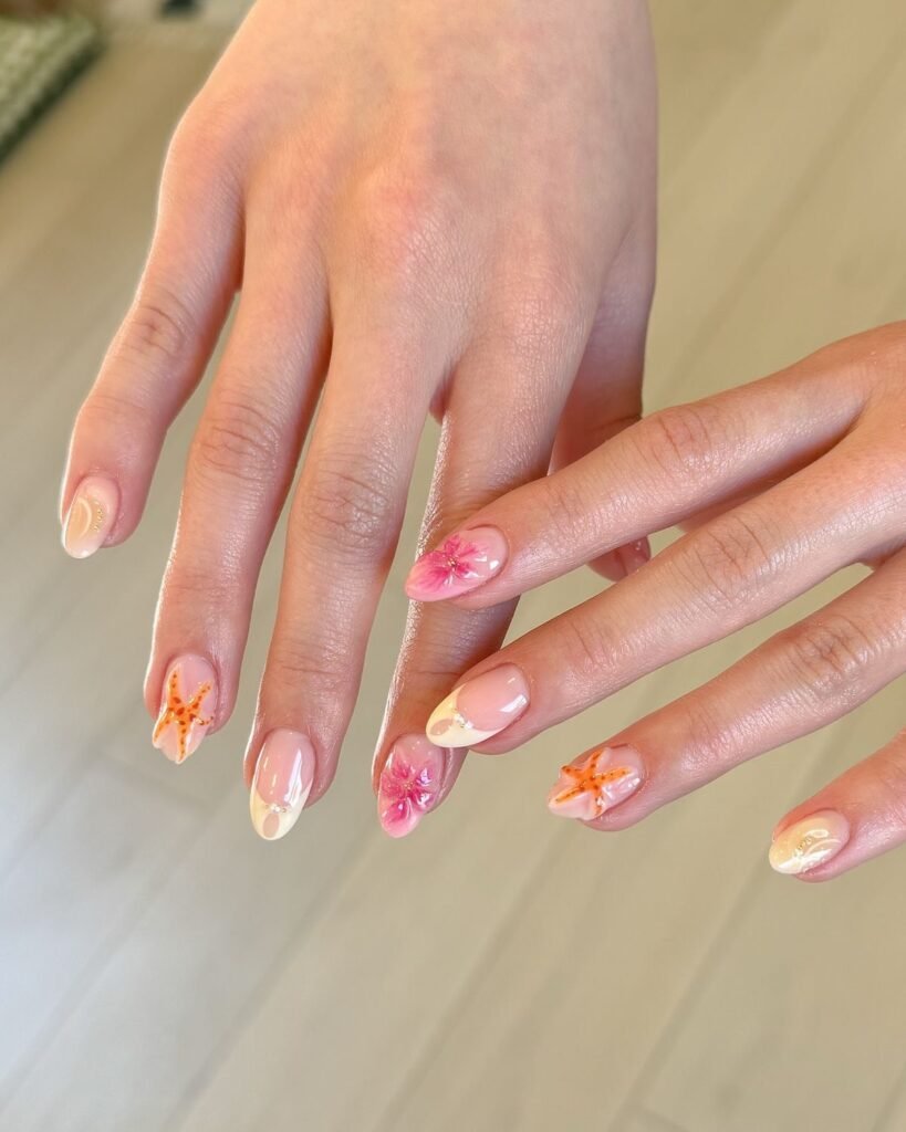 Colorful floral and starfish nail art on manicured hands with a natural background.