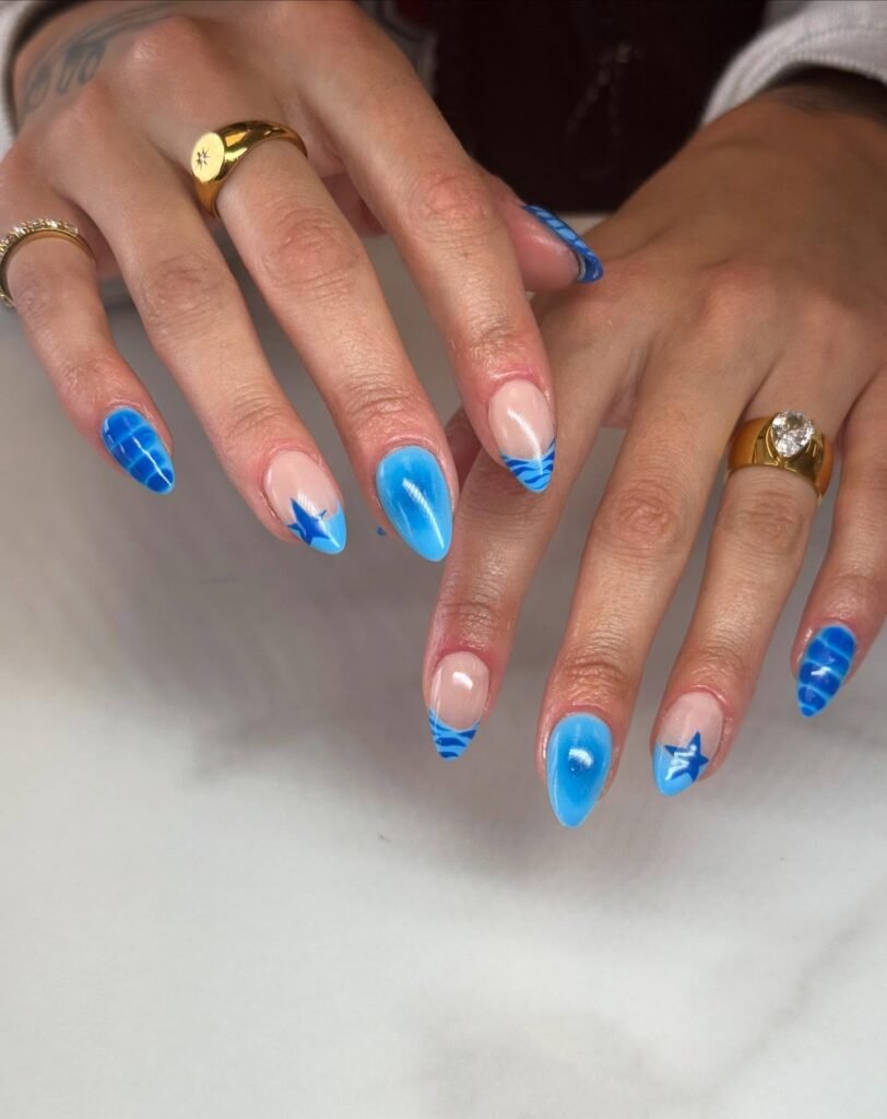 Blue and silver gradient nails with geometric designs and star accents on both hands, showcasing trendy nail art.