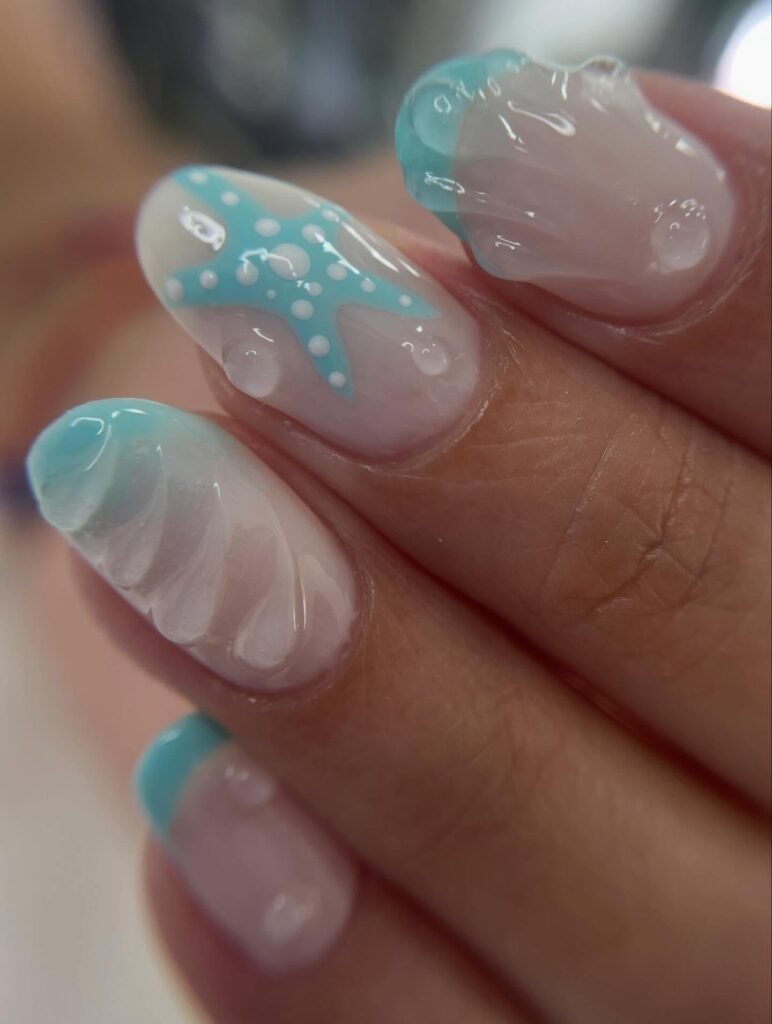 Blue and white starfish-themed nail art with seashell designs, featuring glossy finish.
