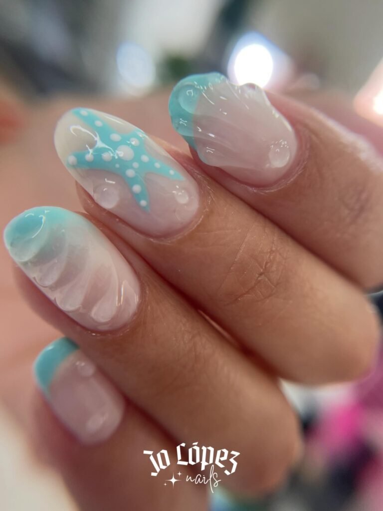 Nautical-themed nail art with starfish and shell designs in blue and white shades.