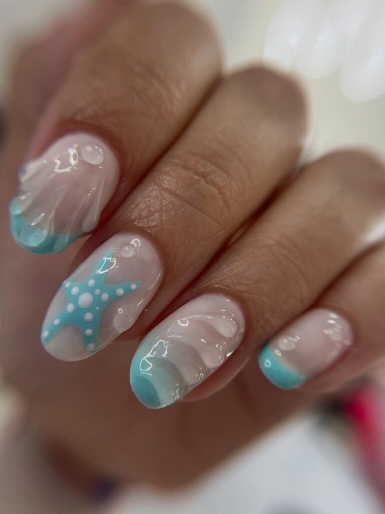 Sea-inspired nail art with blue starfish and wave designs on manicured fingernails.